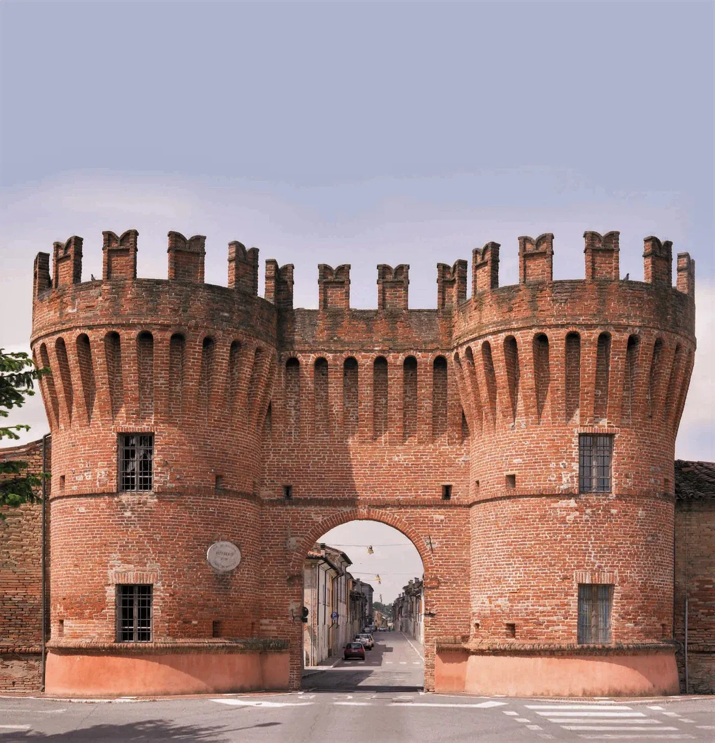 The medieval brick gate of Rivarolo Mantovano under a pale sky